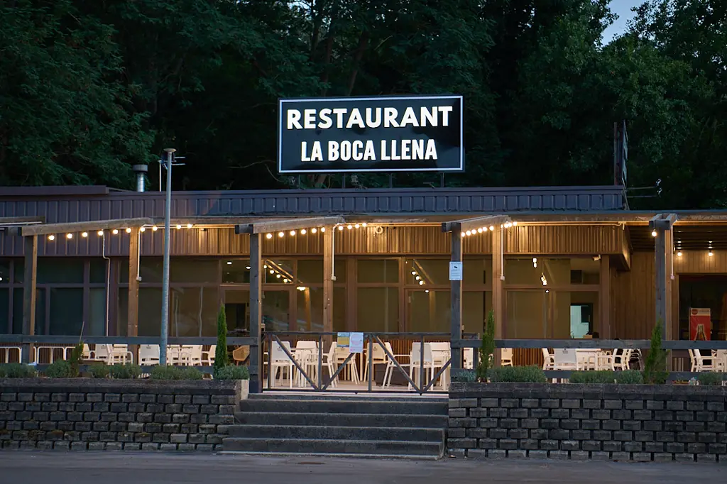 Fachada frontal de La Boca Llena de noche, con la entrada iluminada
