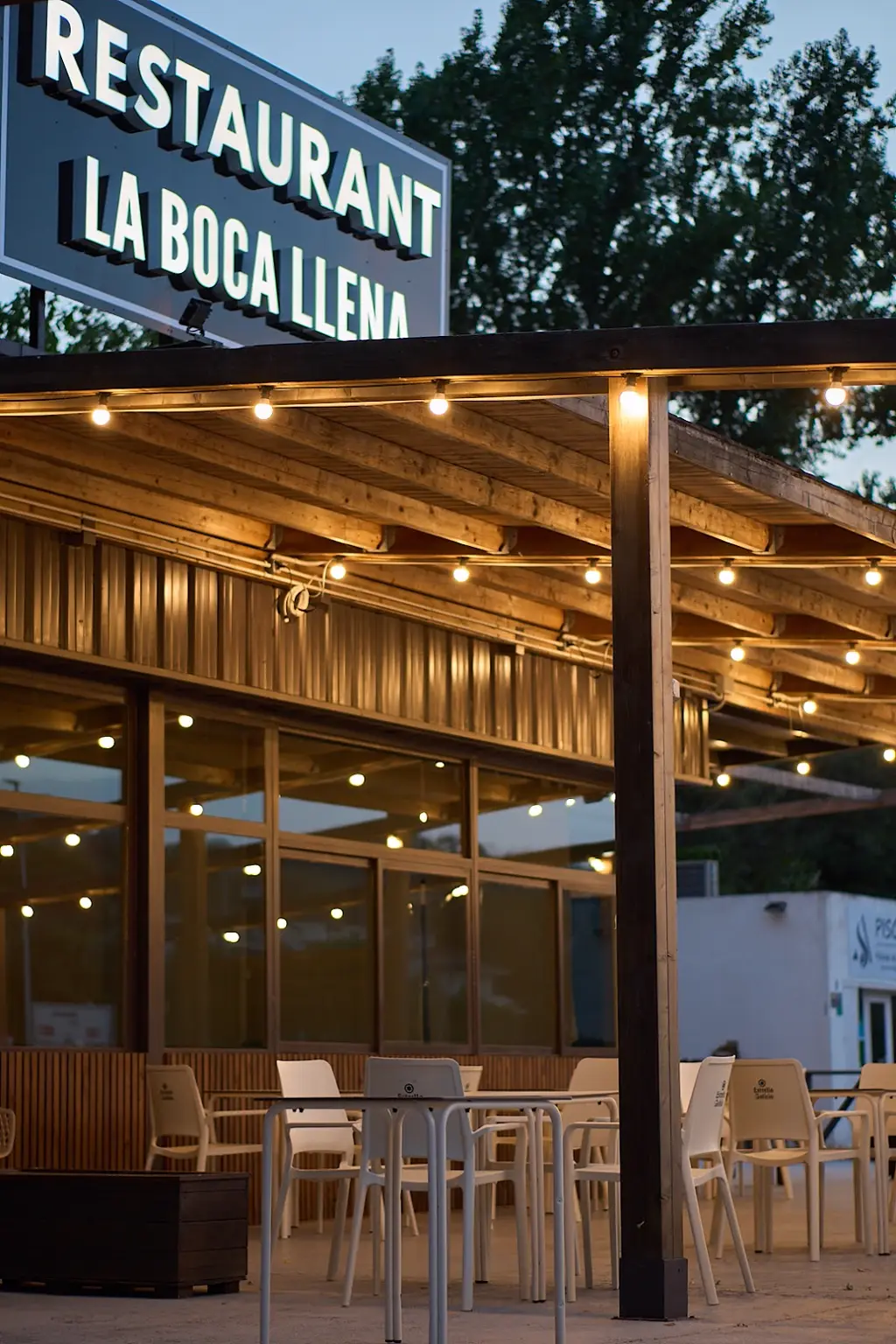 Terraza cubierta con pérgola de madera y luces al atardecer